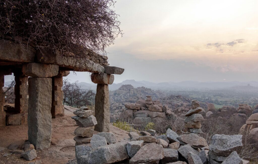 Stunning sunset over ancient stone structures in Hampi, India, showcasing rugged terrain.