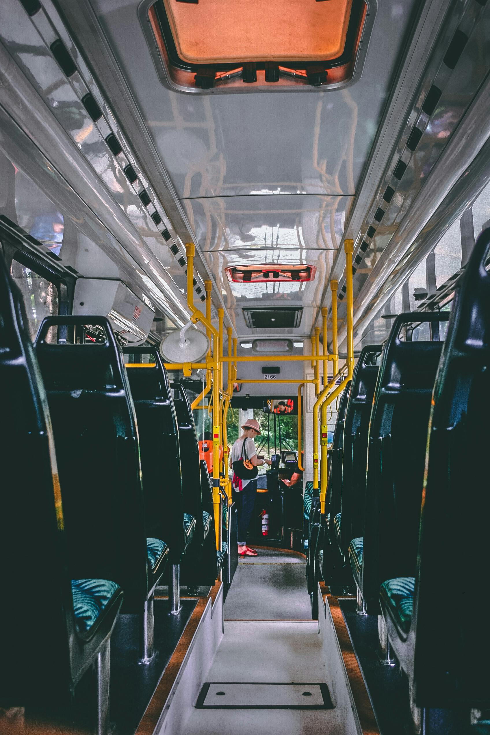 View of a bright and modern public bus interior with passengers standing and sitting, emphasizing public transport.